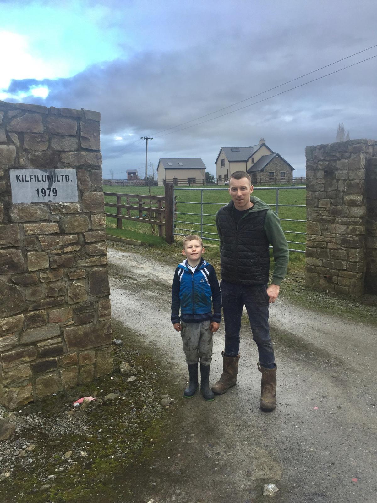 A member of the family and a young helper standing between the stone pillars at the Kilfilum entrance on a County Clare lane.